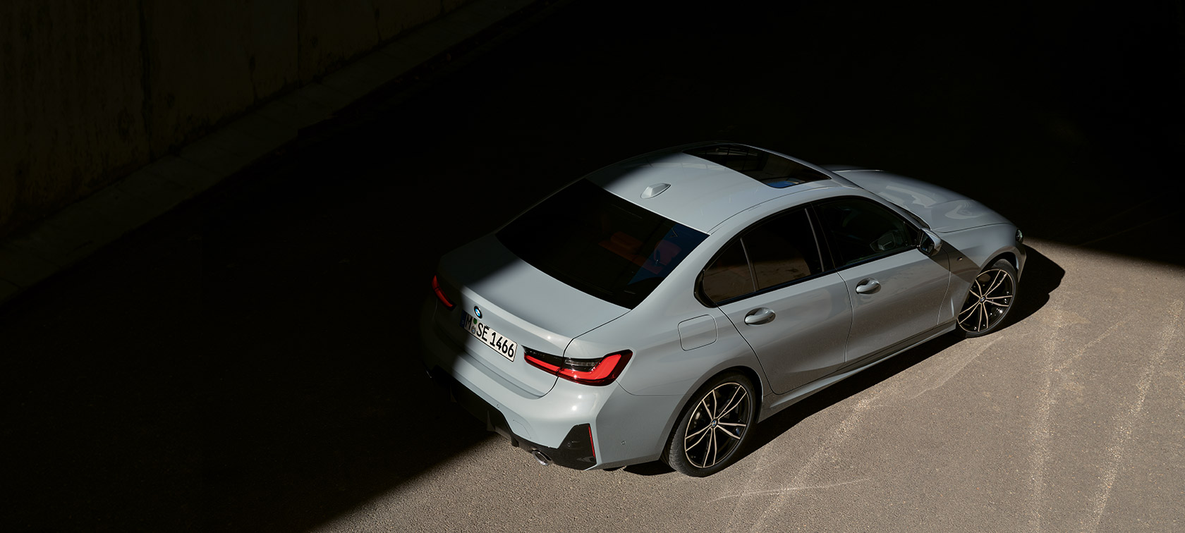 Седан BMW 3 серии LCI G20 в цвете Brookly Grey, вид сзади с поворотом в три четверти с высоты птичьего полета Седан BMW 3 серии LCI G20, вид сзади с поворотом в три четверти с высоты птичьего полета