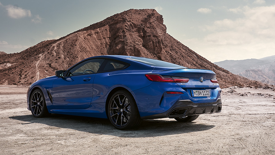BMW 8 Серии Coupé G15 LCI Facelift (рестайлинг 2022 года) с пакетом M Sport в базовой комплектации, вид сзади с поворотом в три четверти BMW 8 Серии Coupé G15 LCI Facelift (рестайлинг 2022 года) с пакетом M Sport в базовой комплектации, цвет Синий Портимау металлик, вид сзади с поворотом в три четверти перед камнями