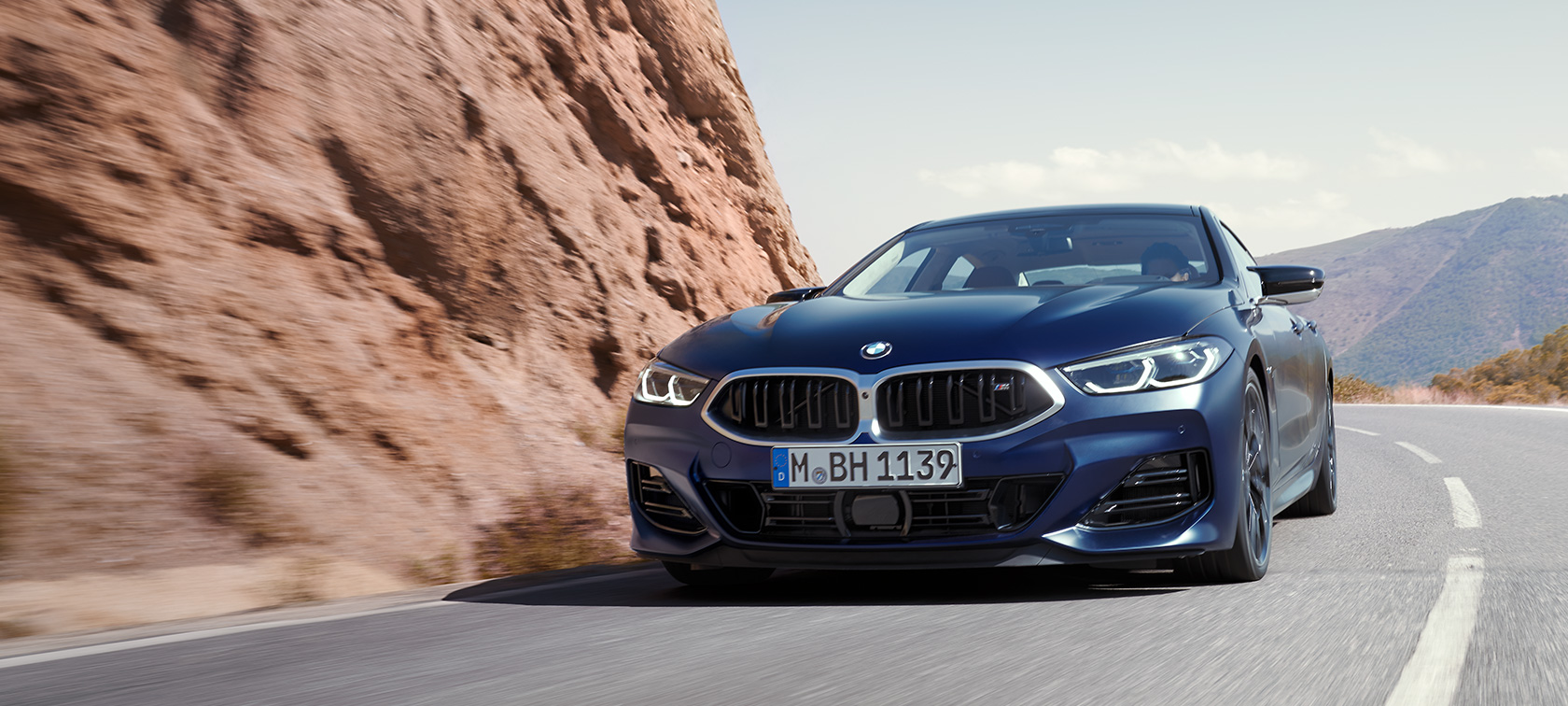 BMW 8 серии Gran Coupé G16 LCI Facelift (рестайлинг 2022 года) в эксклюзивном цвете BMW Individual Морозный Синий Танзанит металлик, вид спереди с поворотом в три четверти, в движении по горной дороге