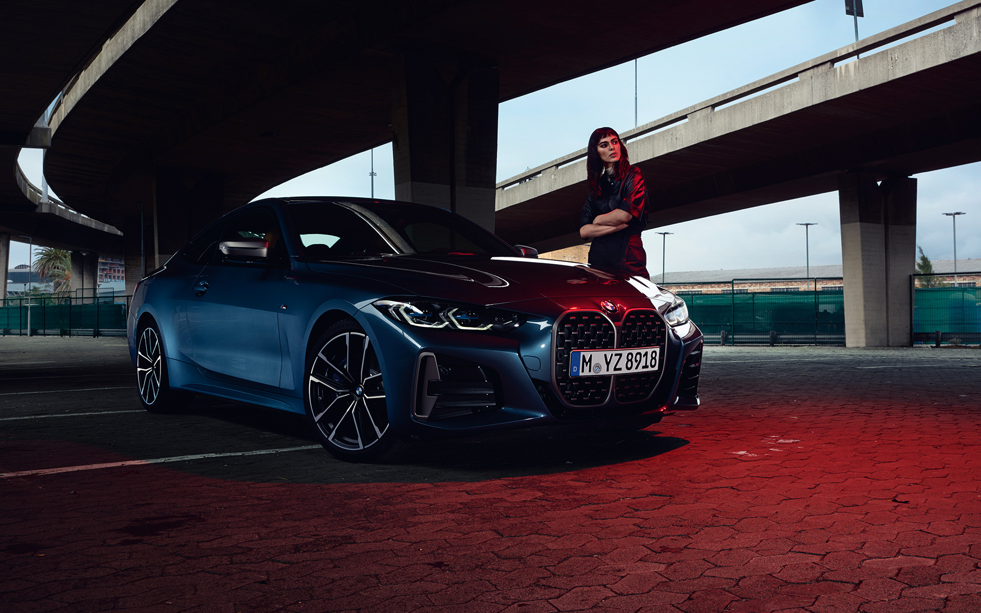 BMW M440i xDrive Coupé G22 2020 G82 2020 в цвете Arctic Race Blue металлик, вид спереди в три четверти с моделью впереди.