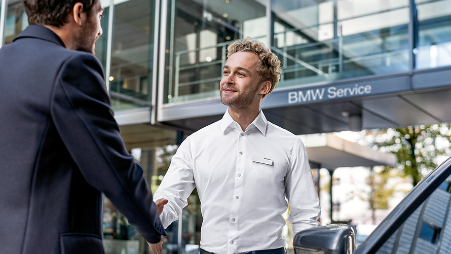 Работник BMW приветствует клиента Работник BMW приветствует клиента