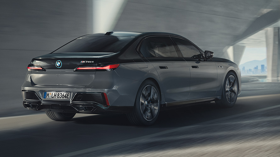 BMW M760e xDrive G70, пакет M Performance BMW M760e xDrive G70, пакет M Performance, BMW Individual двухцветная окраска "Черный Сапфир металлик" и "BMW Individual Серый Дравит металлик", вид сзади в три четверти, в движении на улице