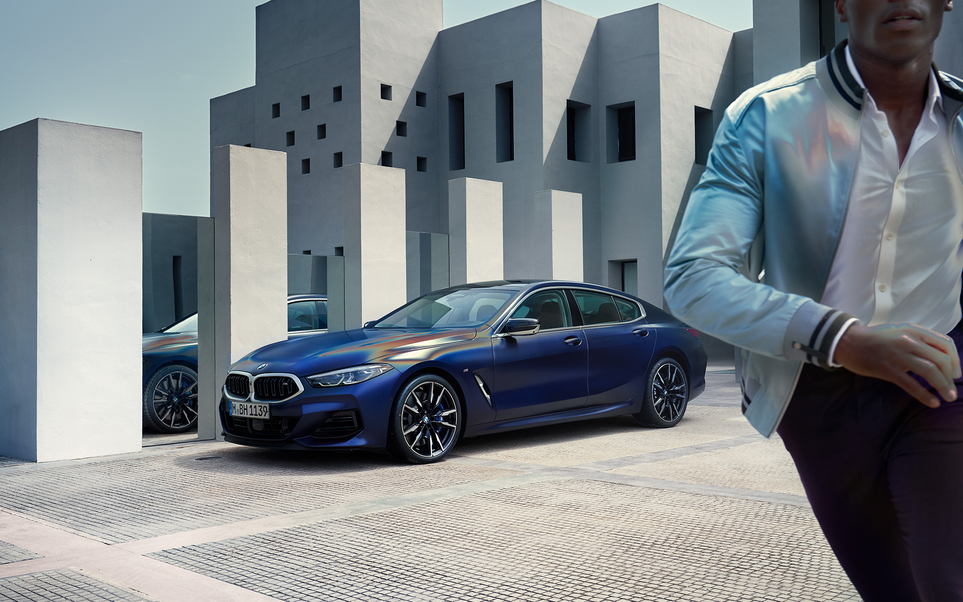 Вид спереди в три четверти BMW M850i xDrive Gran Coupe G16 LCI Facelift 2022 BMW M850i xDrive Gran Coupe G16 LCI Facelift 2022, BMW Individual Морозный Синий Танзанит металлик, вид спереди в три четверти c мужчиной на переднем фоне