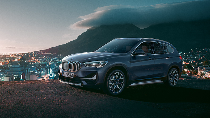 BMW X1 F48 LCI, вид сбоку в три четверти, в статике, перед городским пейзажем