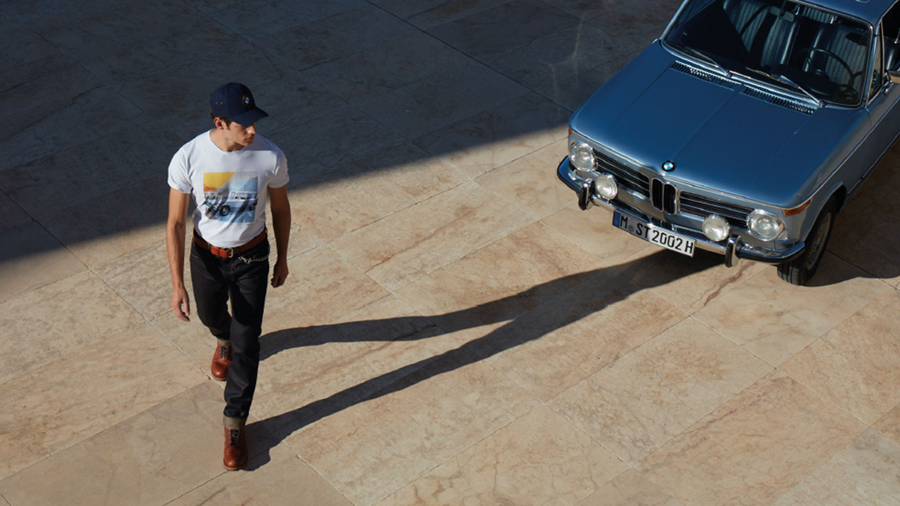 Мужчина в мужской футболке BMW Classic изображен любующимся классическим BMW. Мужчина в мужской футболке BMW Classic изображен любующимся классическим BMW.