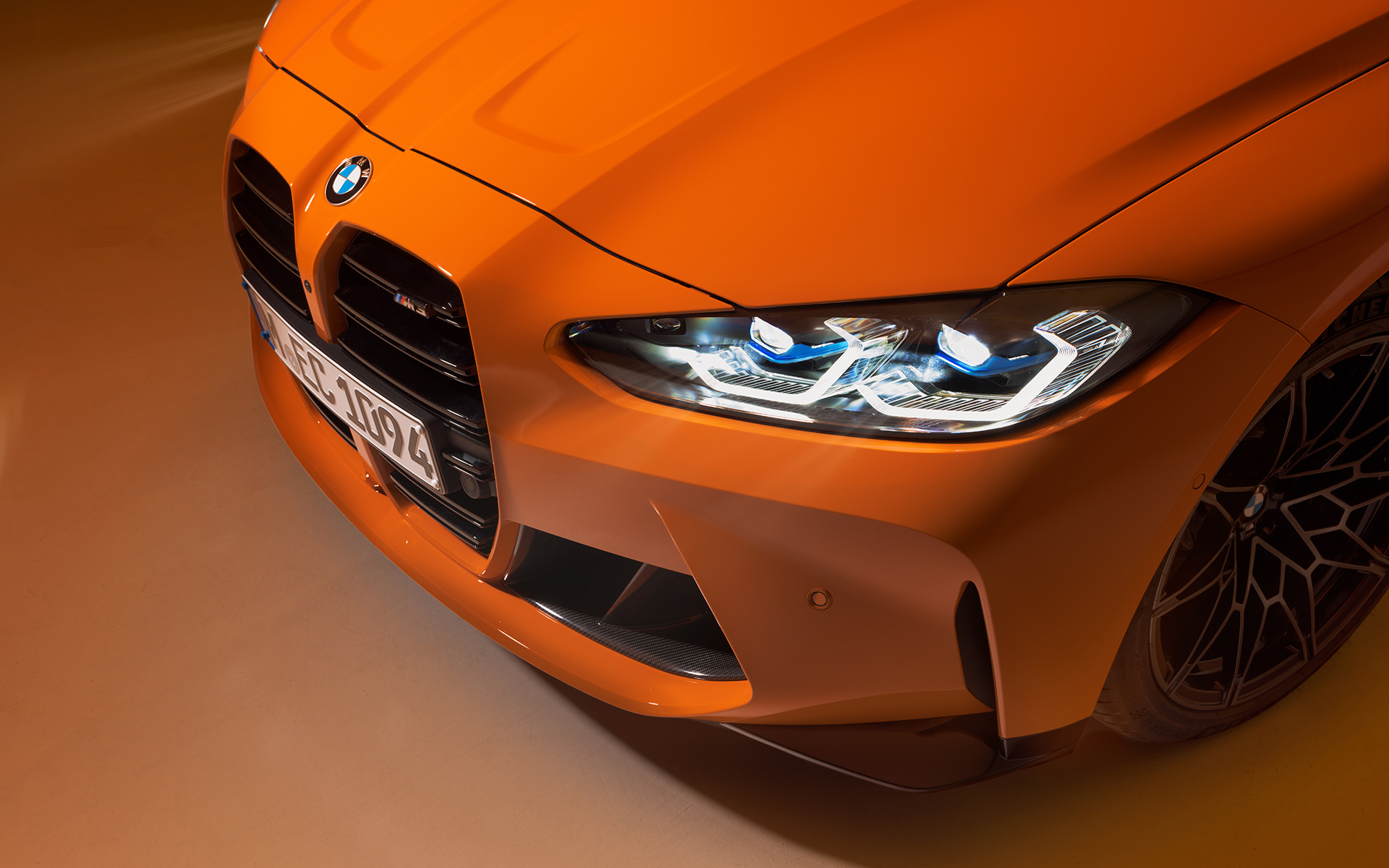 BMW M4 Competition Coupé G82 2021 BMW Individual Fire Orange, вид спереди с поворотом в три четверти BMW M4 Competition Coupé G82 2021 BMW Individual Fire Orange, вид спереди с поворотом в три четверти, вид сверху вблизи
